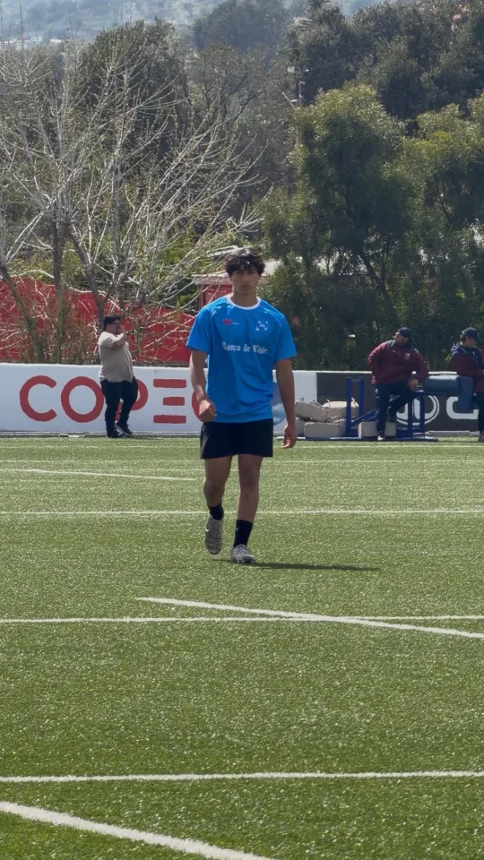 Joaquín cruza la cancha de pasto sintético con la camiseta celeste de entrenamiento