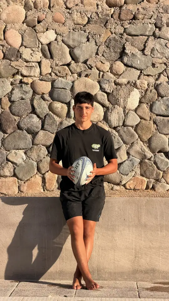 Joaquín sostiene el balón de rugby apoyado en un muro de piedra
